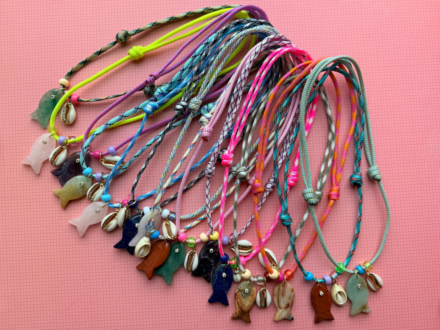 Colorful bracelets with various charms on a pink background